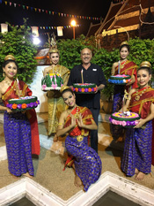 Stephen Cervantes in Thailand holding a cake, surrounded by costumed Thai people